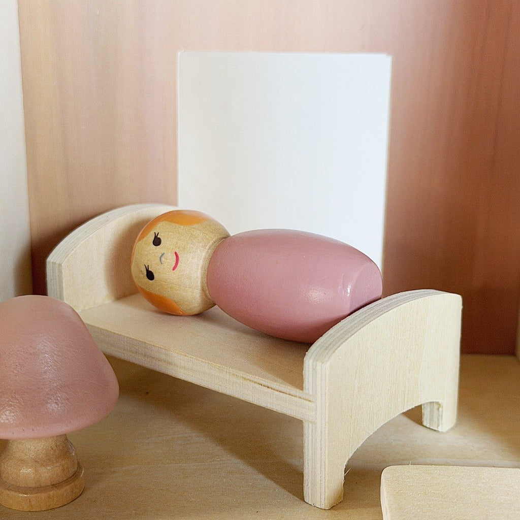 Peg doll in wooden bed