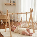 Baby playing under Bear's Busy Gym wooden play gym
