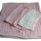 Pink and white baby blanket with textured surface on a light gray background