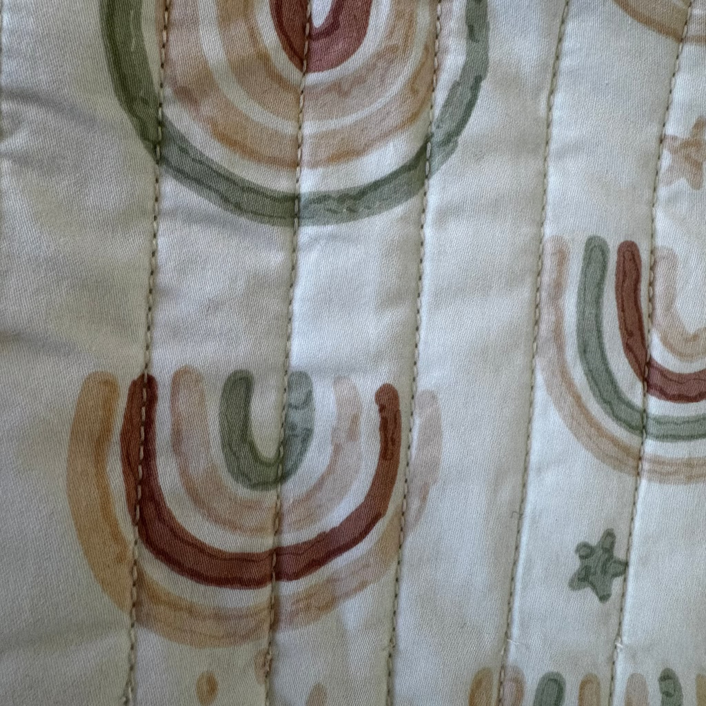 Close-up of fabric with abstract patterns in brown, green, and beige on a beige background.