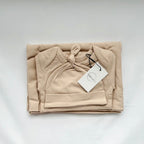 Folded beige baby hoodie with a tag on a white background