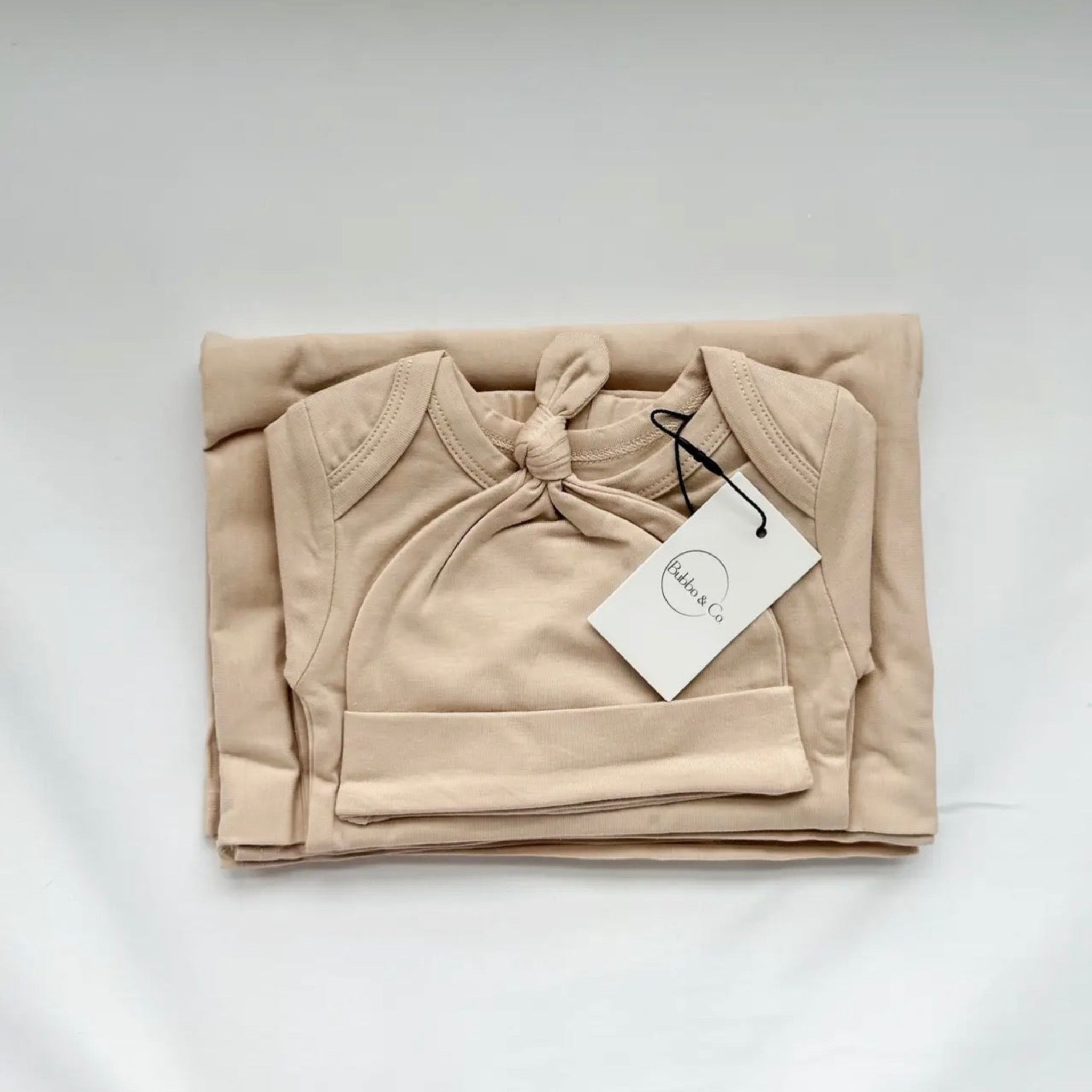 Folded beige baby hoodie with a tag on a white background