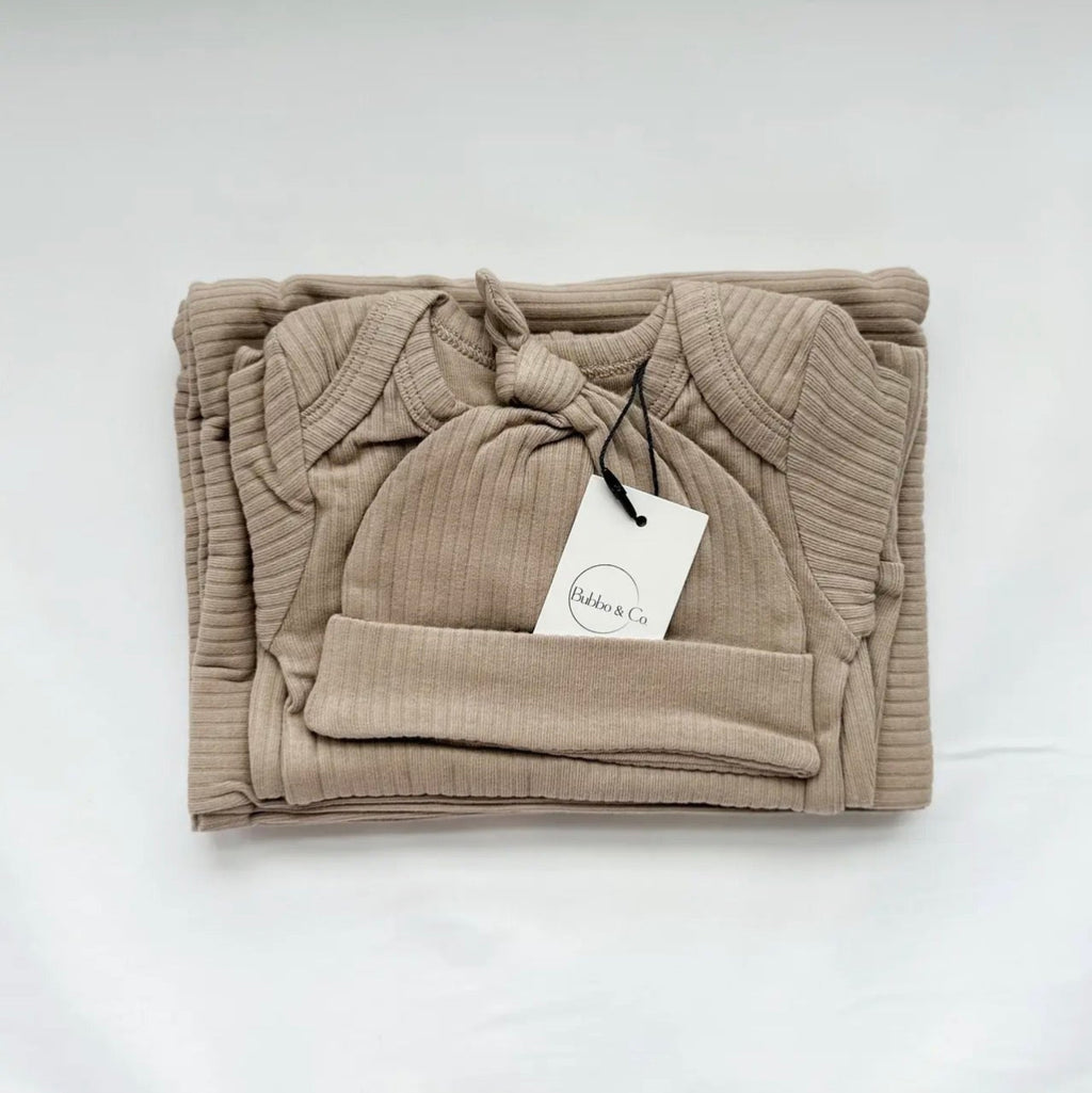 Folded beige baby outfit with a hat on a white background
