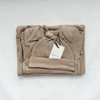 Folded beige baby outfit with a hat on a white background