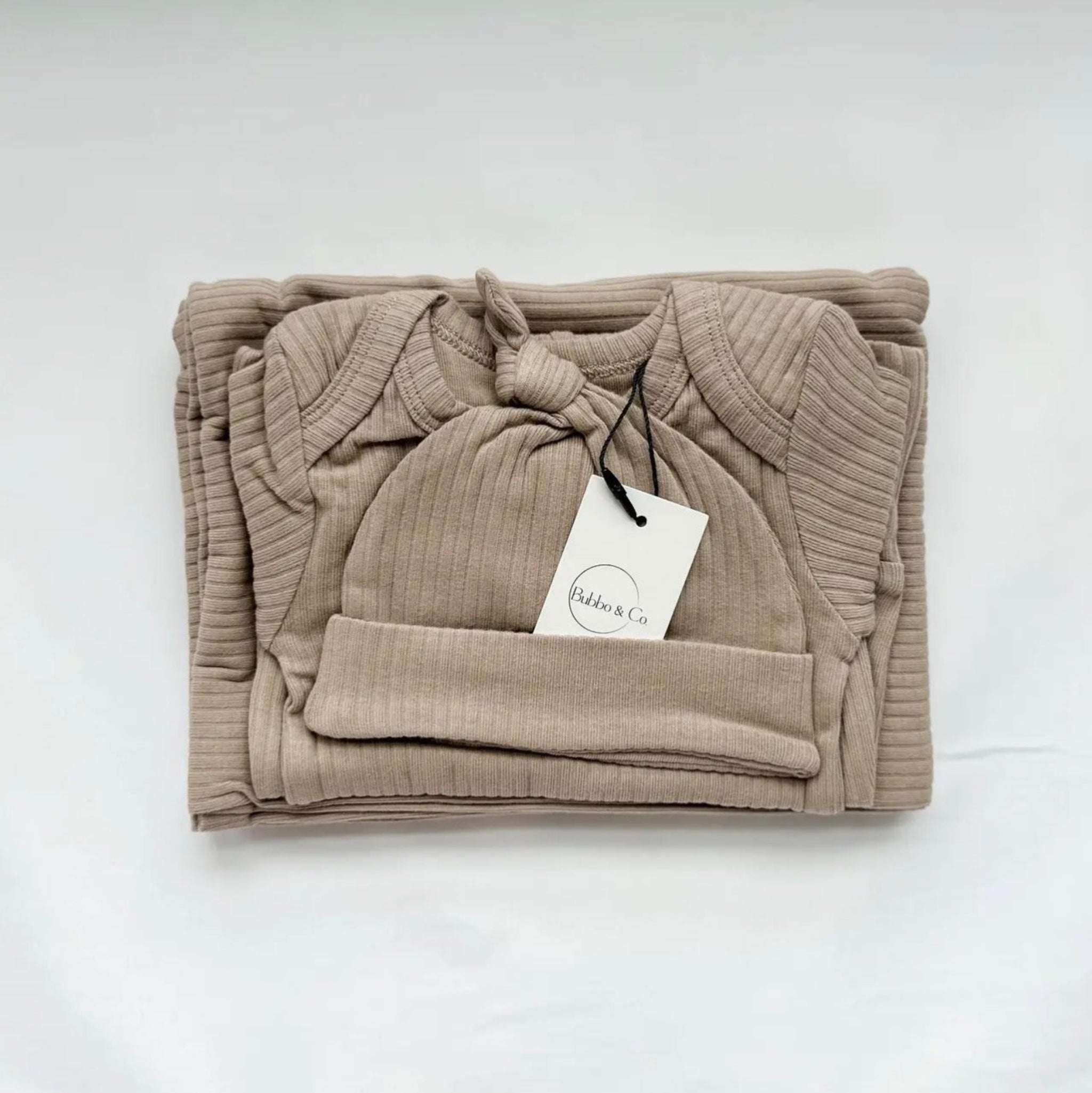 Folded beige baby outfit with a hat on a white background