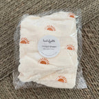 Package of a folded fabric item with a label on a textured brown background