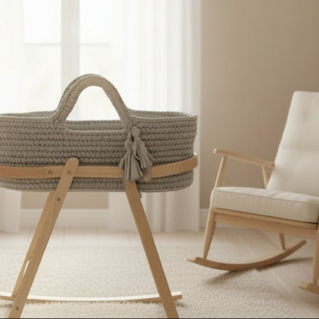 Gray woven baby bassinet with wooden stand on a white background