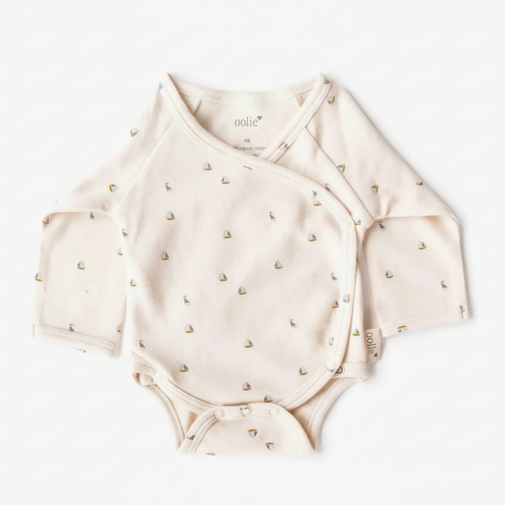 Beige baby onesie with small patterns on a white background
