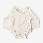 Beige baby onesie with small patterns on a white background