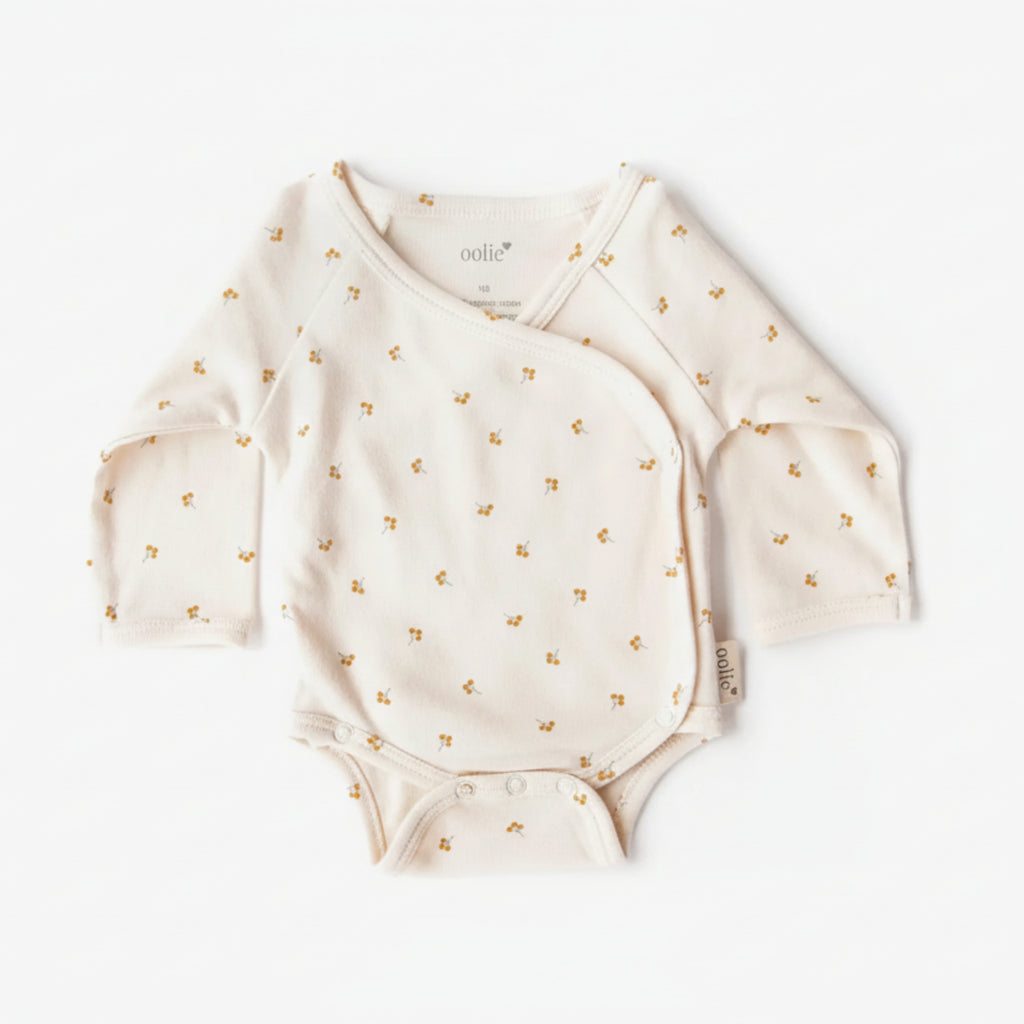 White baby onesie with gold floral patterns on a white background
