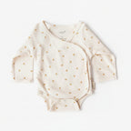 White baby onesie with gold floral patterns on a white background