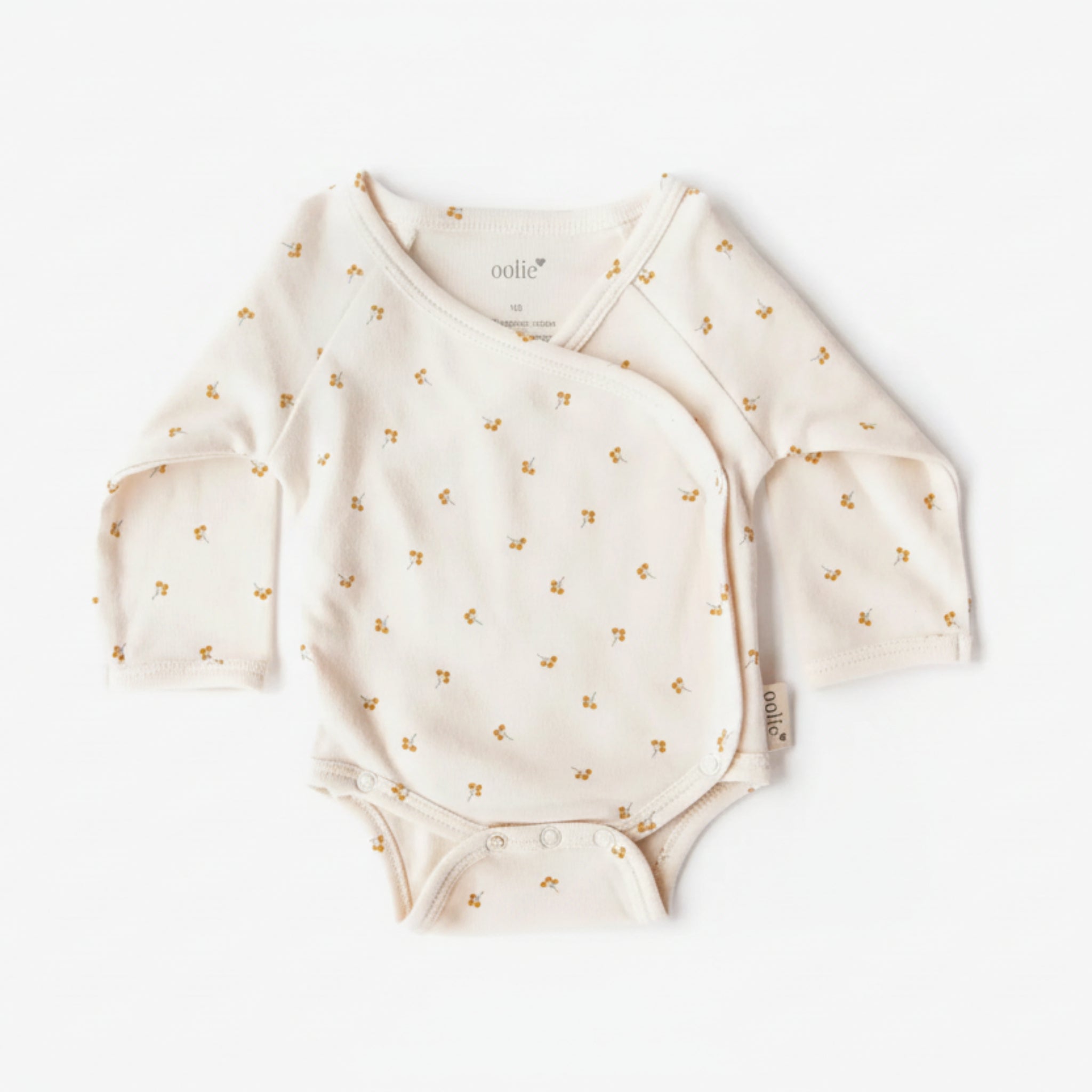 White baby onesie with gold floral patterns on a white background
