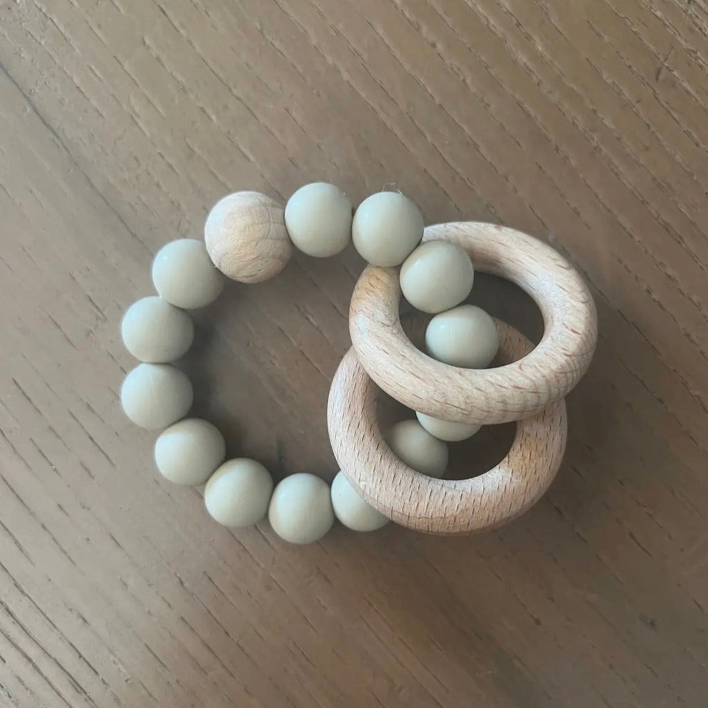 Wooden teething ring with beads on a wooden surface