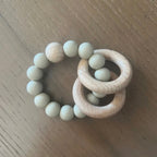 Wooden teething ring with beads on a wooden surface