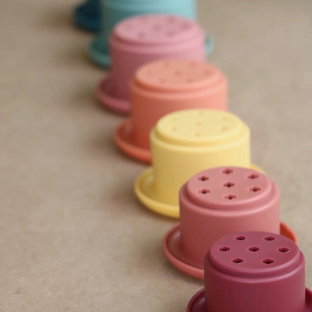 Set of colorful plastic planters on a beige surface