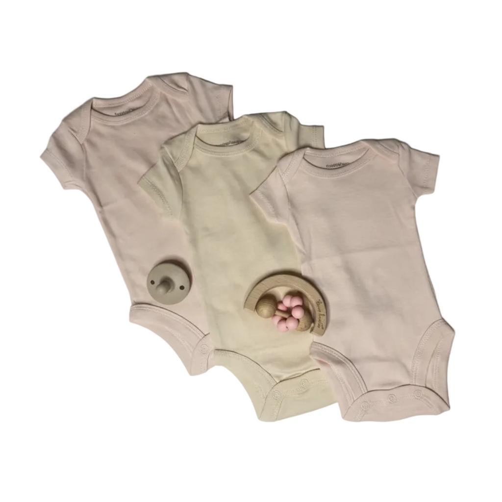 Three baby bodysuits, two pink and one tan, on a white background