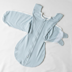 Light blue baby onesie with mittens on a beige surface