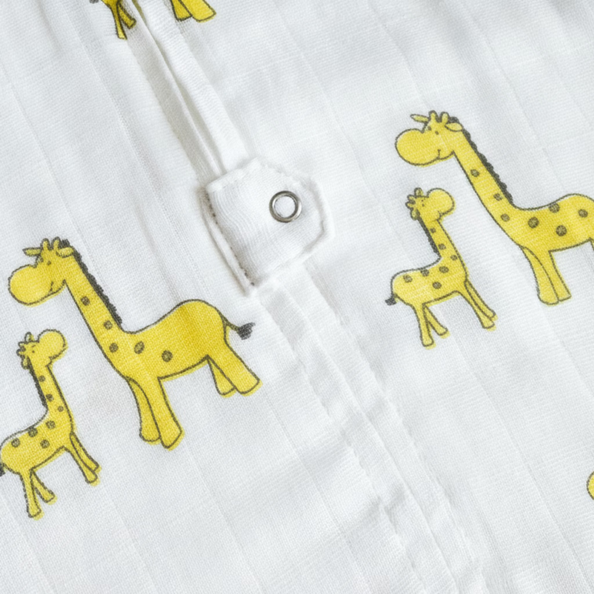 Close-up of white fabric with yellow animal prints, including giraffes and elephants.