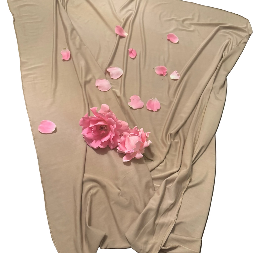 Beige fabric with pink flowers and petals on a wooden surface