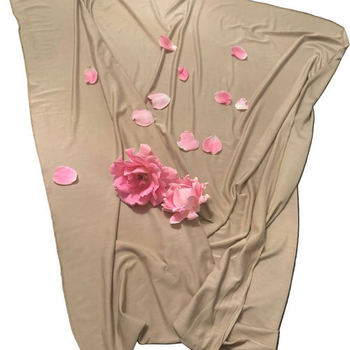 Beige fabric with pink flowers and petals on a wooden surface