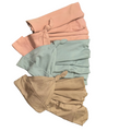 Three folded pieces of swaddles in pink, blue green, and beige on a wooden surface