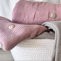 Knitted blankets in pink and gray with embroidered flowers on a white background