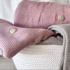 Knitted blankets in pink and gray with embroidered flowers on a white background