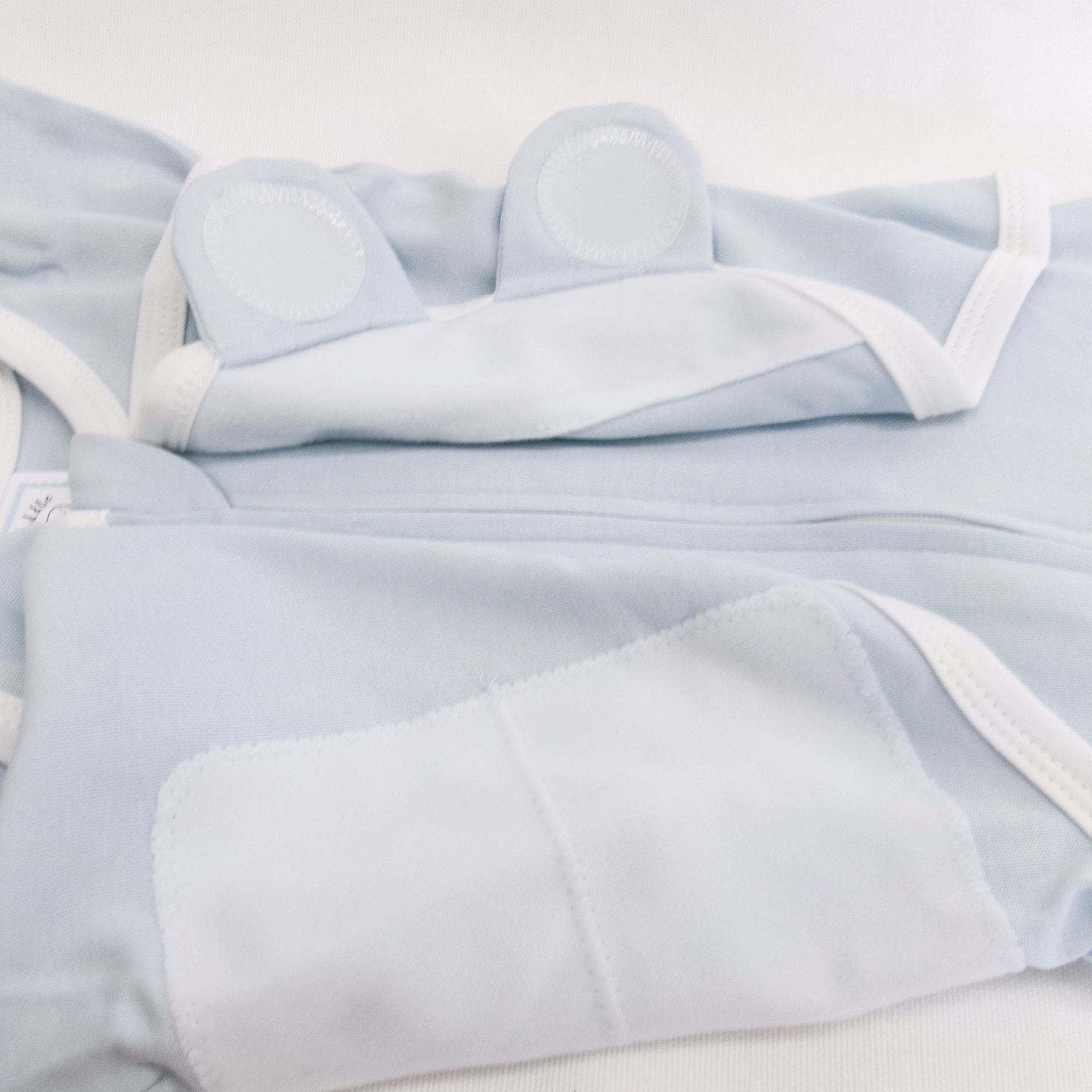 Light blue baby outfit with white trim on a light gray background