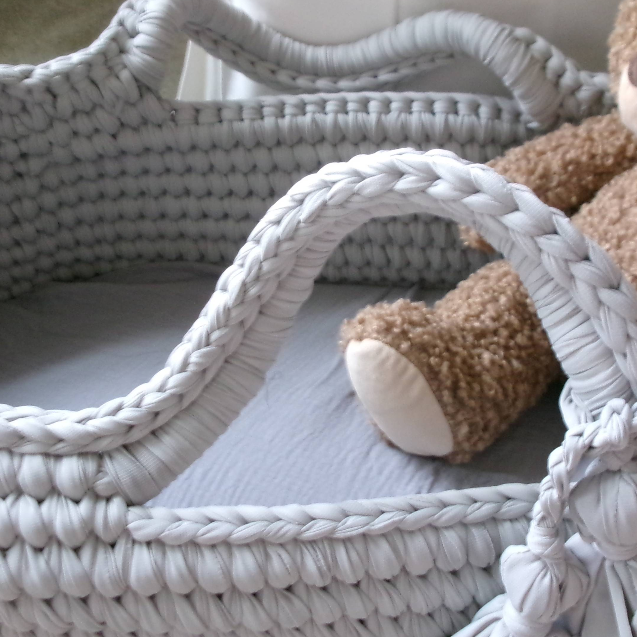 Brown teddy bear in a woven basket on a wooden floor